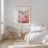 a bedroom with a bed, a woven chair, and a framed poster of a flower market in Stockton.