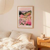 a bedroom scene with a framed poster of a mountain landscape hanging on the wall above a bed with striped pillows.