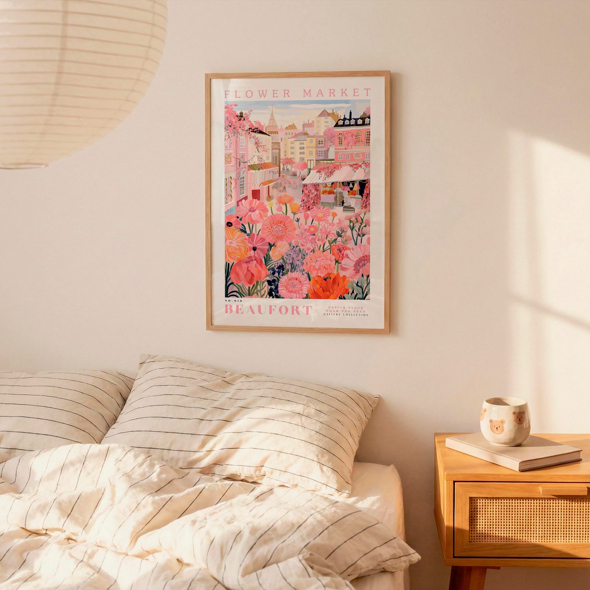 a bedroom scene with a framed poster of a flower market hanging on the wall above a bed with striped pillows.