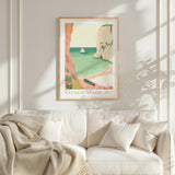 a framed poster of a beach scene with a boat, hanging on a wall above a white couch with a blanket draped over it.