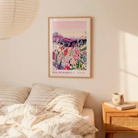 a bedroom scene with a framed poster of a colorful floral landscape hanging on the wall above a bed with striped pillows.