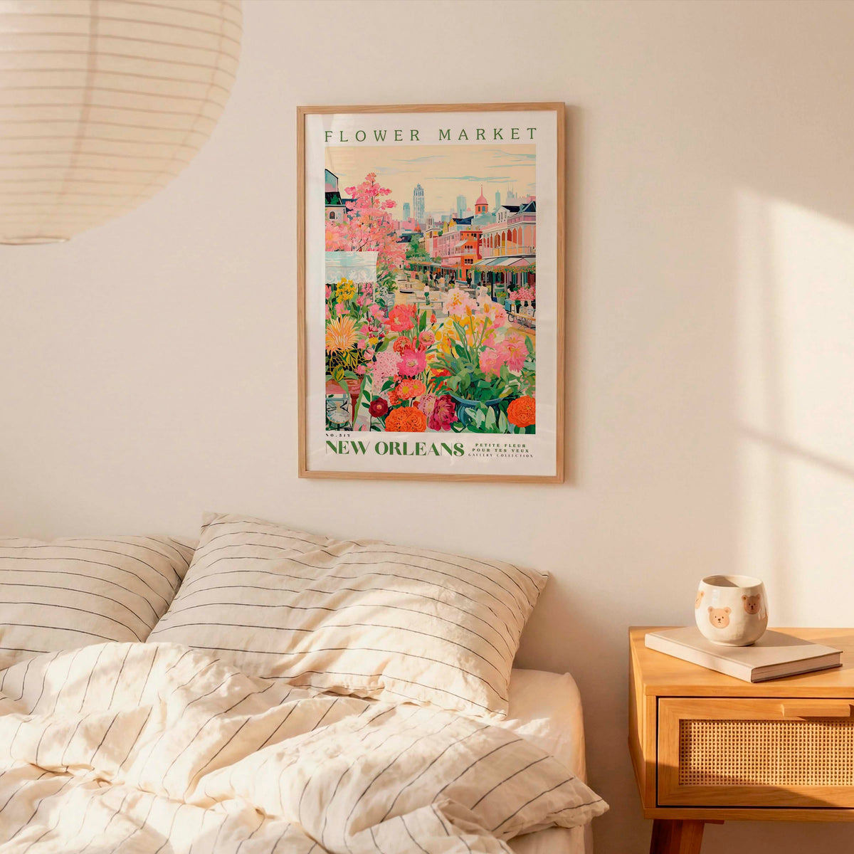 a framed poster of a colorful floral scene hanging on a wall above a bed with striped pillows.