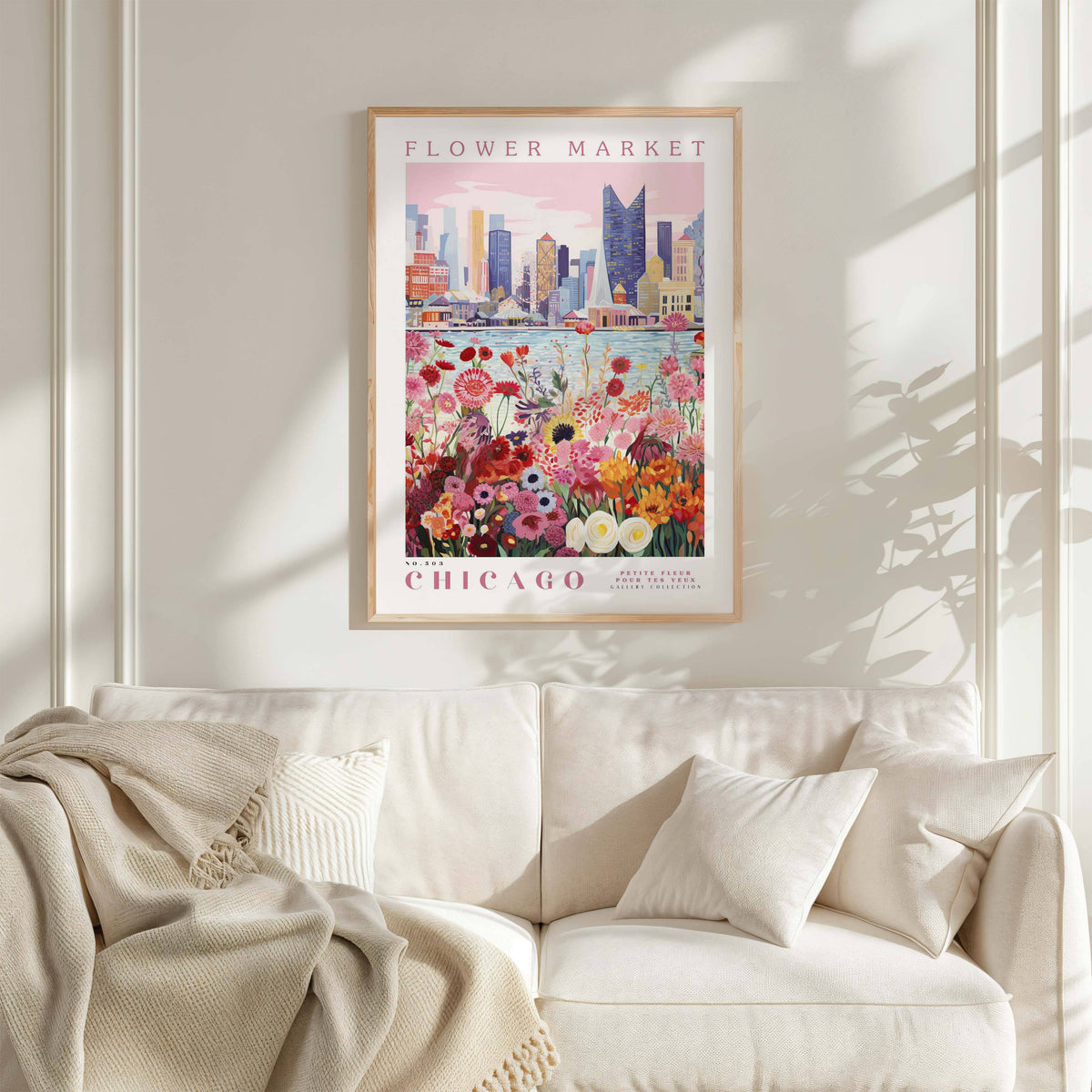 a poster of a cityscape with a flower market in the foreground, hanging on a wall above a white couch.