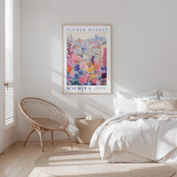 a bedroom with a large poster of a colorful cityscape hanging on the wall, a woven chair, and a bed with white bedding.