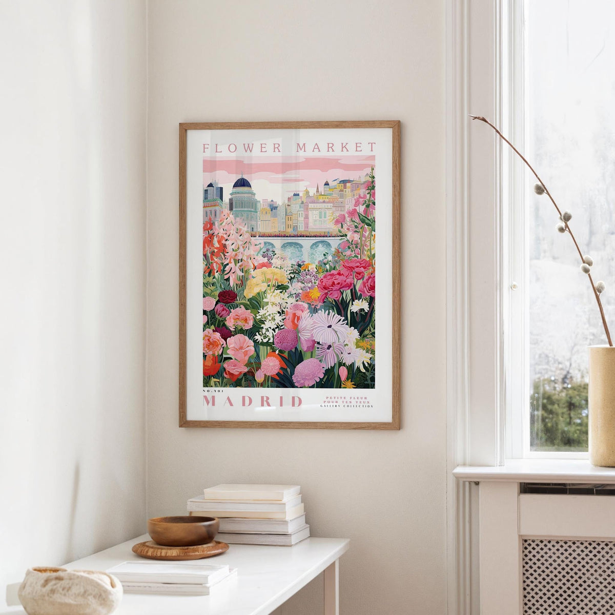 a framed poster of a colorful garden scene with flowers hanging on a wall in a room.