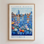 The image is a framed poster depicting a vibrant flower market in Rotterdam, Netherlands. The poster showcases a variety of colorful flowers and plants arranged in vases, set against the backdrop of the city's distinctive architecture. The text on the poster reads "FLOWER MARKET" and "NEW YORK ROTTERDAM POTÉ TÉ FEU, GALLERY COLLECTION".