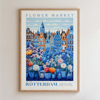 The image is a framed poster depicting a vibrant flower market in Rotterdam, Netherlands. The poster showcases a variety of colorful flowers and plants arranged in vases, set against the backdrop of the city's distinctive architecture. The text on the poster reads "FLOWER MARKET" and "NEW YORK ROTTERDAM POTÉ TÉ FEU, GALLERY COLLECTION".