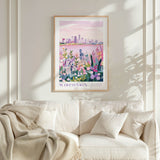 a framed poster of a cityscape with a floral background, hanging on a wall above a white couch with a blanket draped over it.