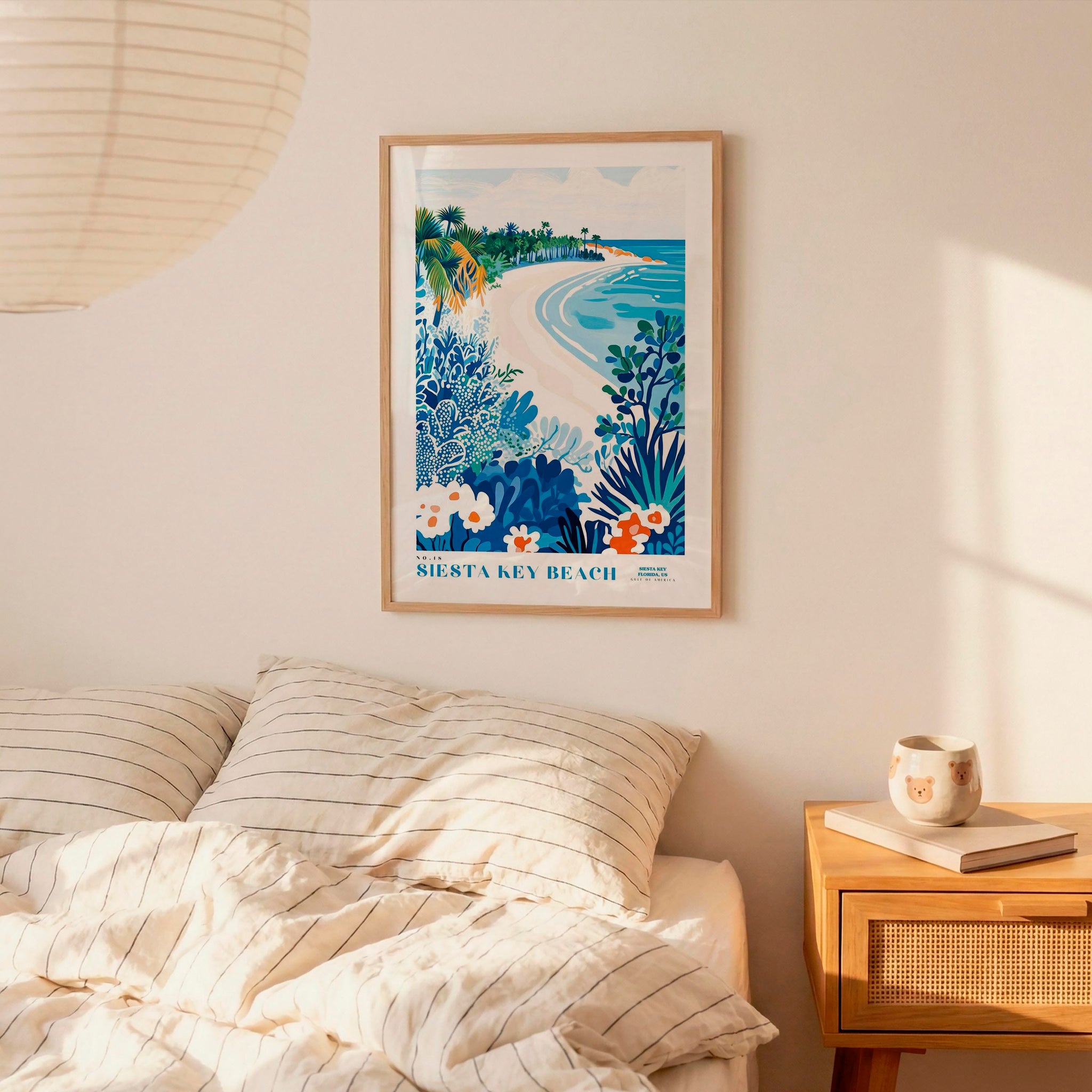 a bedroom with a bed, a nightstand, and a framed poster of a beach scene hanging on the wall.