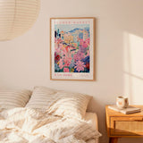 a bedroom scene with a framed poster of a colorful floral scene hanging on the wall above a bed with striped pillows.