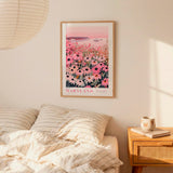 a bedroom scene with a framed poster of a field of flowers hanging on the wall above a bed with striped pillows.