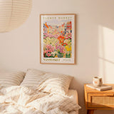 a bedroom setting with a framed poster of a flower market in Santoku, New Hampshire, hanging on the wall above a bed with striped pillows.