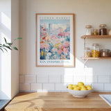 a kitchen counter with a bowl of lemons, a framed poster of a flower market in San Antonio, and a shelf with jars and containers.