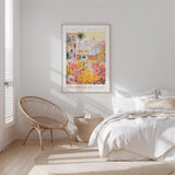 a bedroom with a bed, a woven chair, and a framed poster of a colorful floral scene hanging on the wall.