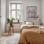 a cozy bedroom with a large bed, a nightstand with a plant, and a framed poster of a cityscape on the wall.