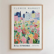 The image is a framed poster depicting a colorful cityscape with a variety of flowers and plants in the foreground.