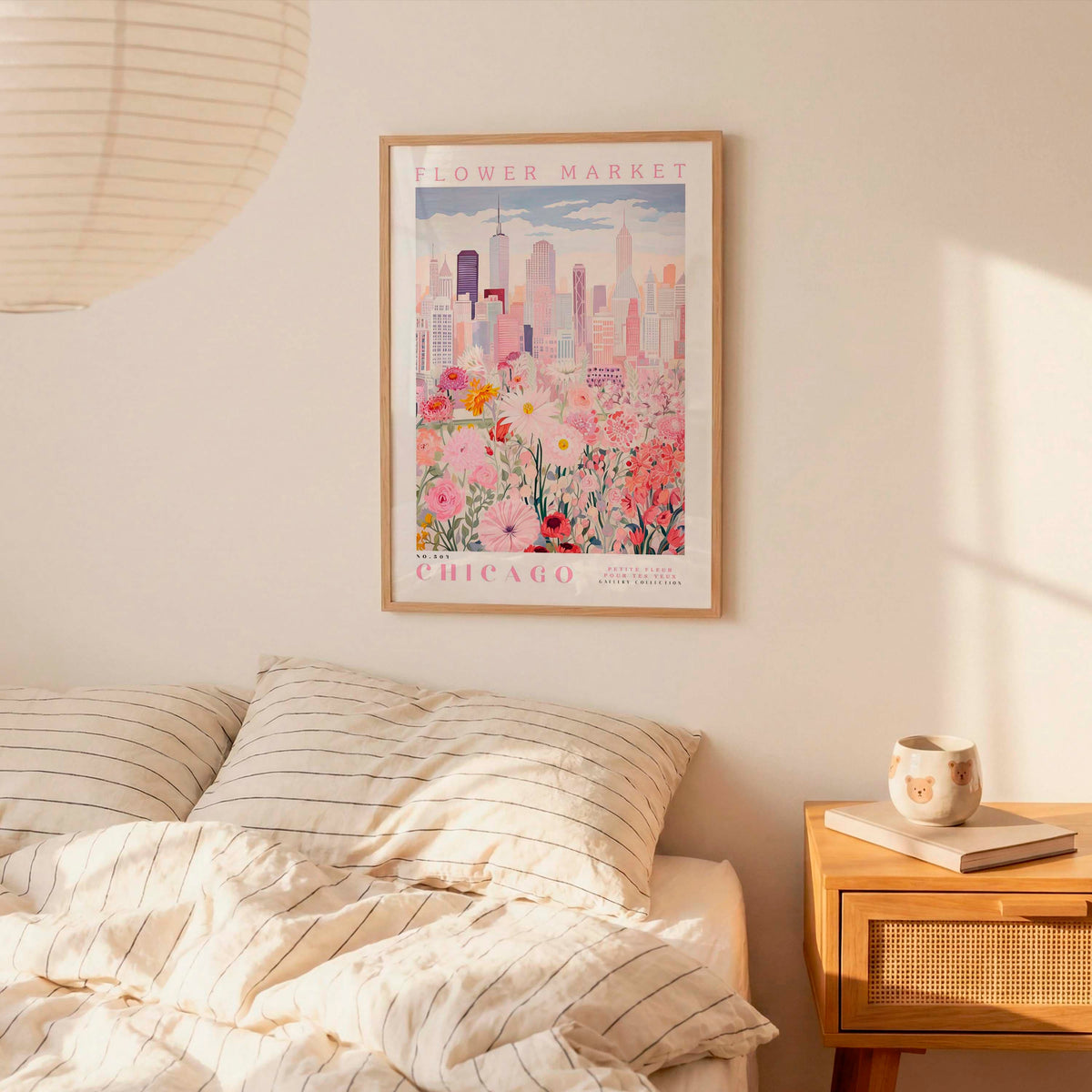 a framed poster of a cityscape with flowers hanging on a wall above a bed with striped pillows.