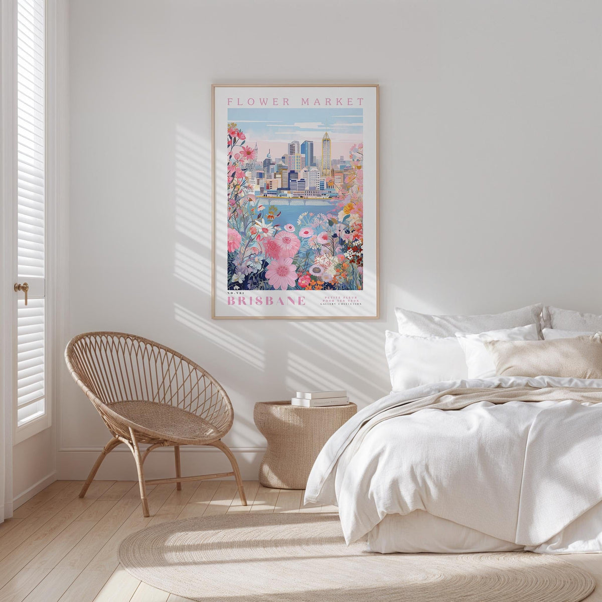 a bedroom with a large poster of the Brisbane Flower Market hanging on the wall. The poster depicts a cityscape with a river and flowers, creating a vibrant and colorful scene. The room is decorated with a white bed, a woven chair, and a small side table. The overall atmosphere of the room is bright and inviting, with the poster serving as a focal point and adding a touch of whimsy to the space.