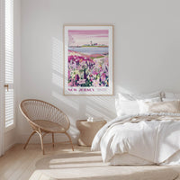 A bedroom with a large poster of a field of flowers hanging on the wall, a woven chair, and a bed with white bedding.