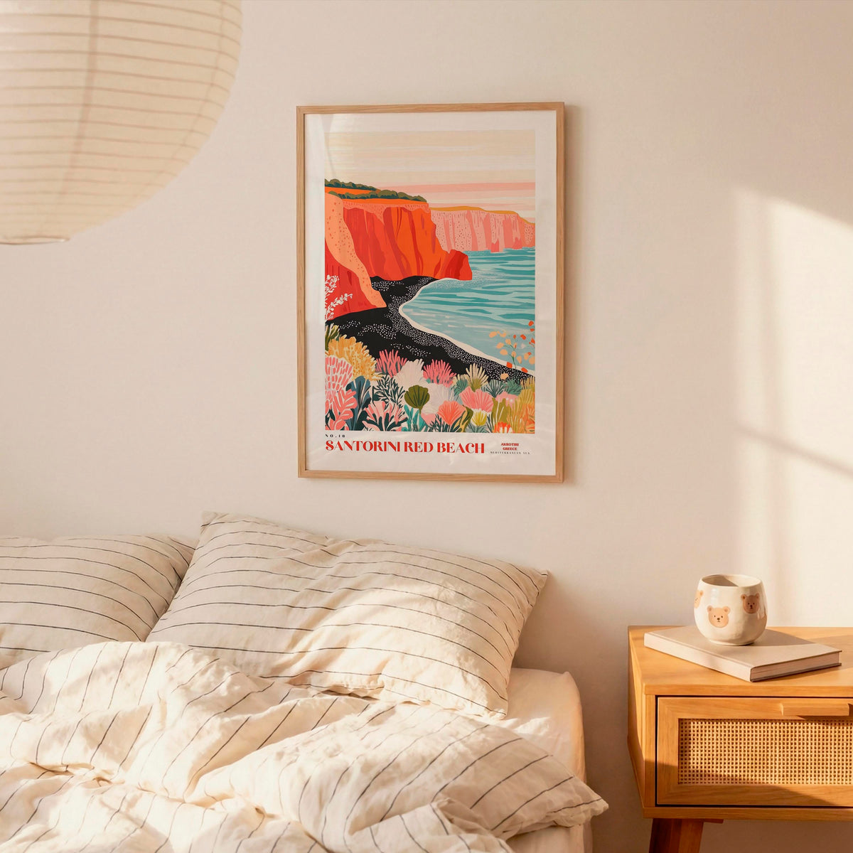 a bedroom with a bed, a nightstand, and a framed poster of a coastal landscape hanging on the wall.