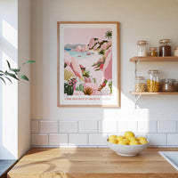 a kitchen scene with a framed poster of a tropical beach landscape hanging on the wall above a wooden countertop with a bowl of lemons.