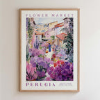The image is a framed poster depicting a vibrant flower market in Perugia, Italy. The poster showcases a variety of colorful flowers and plants, with a person walking through the market. The text on the poster reads "FLOWER MARKET" and "PERUGIA", indicating the location and the name of the market.