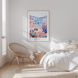 a bedroom with a bed, a wicker chair, and a framed poster of a flower market on the wall.
