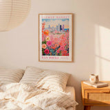 a bedroom setting with a framed poster of a colorful floral scene hanging on the wall above a bed with striped pillows.