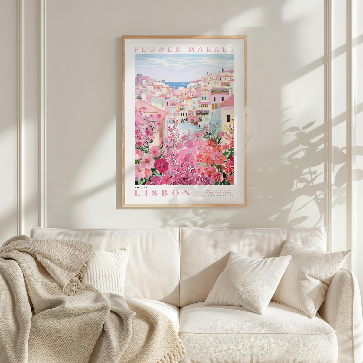 a framed poster of a cityscape with pink flowers hanging on a wall above a white couch.