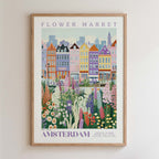 The image is a framed poster depicting a colorful and vibrant flower market in Amsterdam, with a variety of flowers and plants in the foreground and a cityscape in the background.