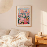 a bedroom setting with a framed poster of a colorful floral scene hanging on the wall above a bed with striped pillows.