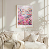 a framed poster of a colorful floral scene hanging on a wall above a white couch with pillows.
