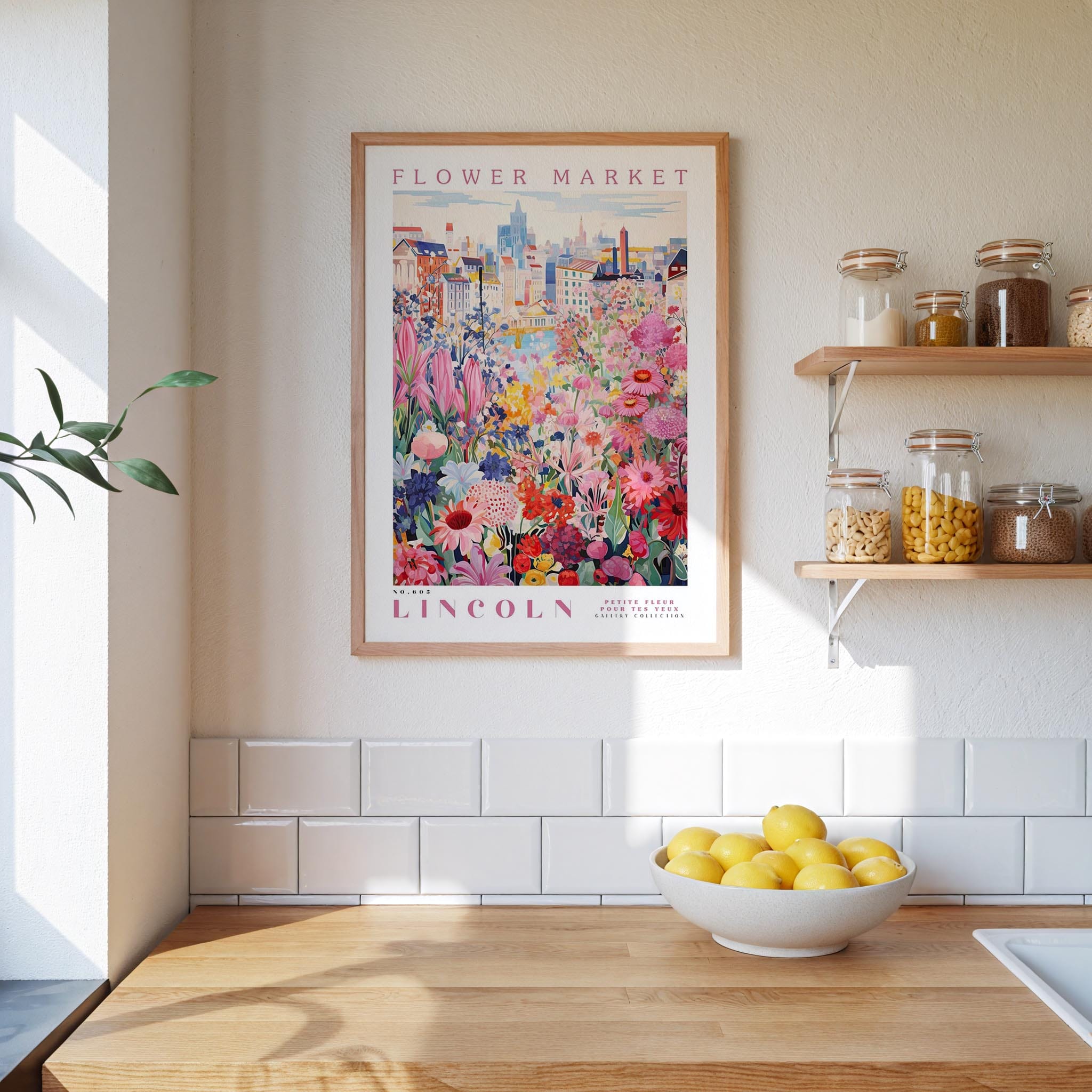 a framed poster of a colorful floral scene hanging on a wall above a wooden countertop with a bowl of lemons.