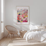 a bedroom with a bed, a wicker chair, and a framed poster of a flower market on the wall.