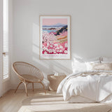 A bedroom with a large bed, a woven chair, and a framed poster of a floral landscape hanging on the wall.