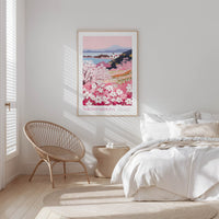 A bedroom with a large bed, a woven chair, and a framed poster of a floral landscape hanging on the wall.