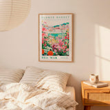 a bedroom setting with a framed poster of a colorful garden hanging on the wall above a bed with striped pillows.
