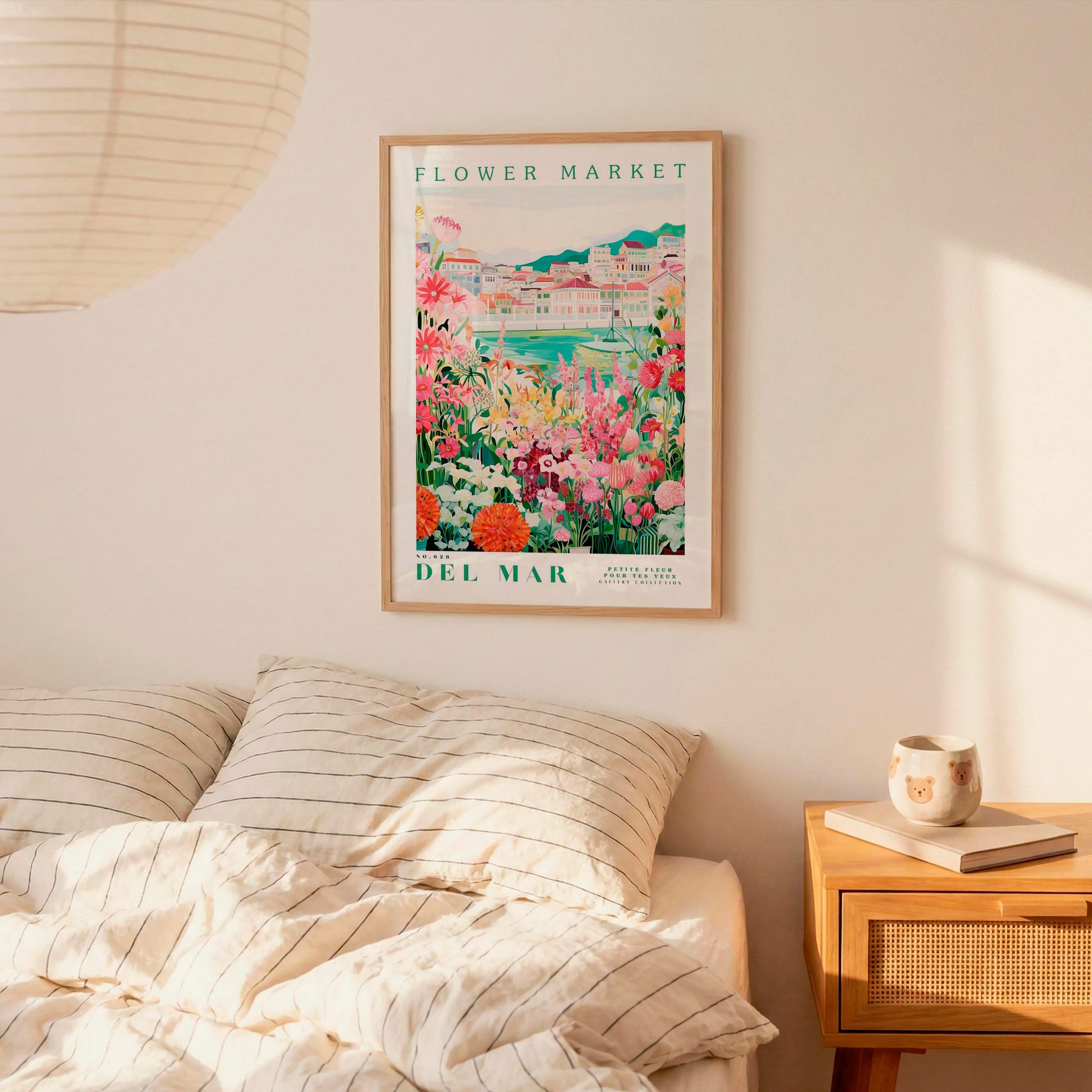a bedroom setting with a framed poster of a colorful garden hanging on the wall above a bed with striped pillows.