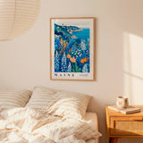 a bedroom scene with a framed poster of a coastal landscape hanging on the wall above a bed with striped pillows.