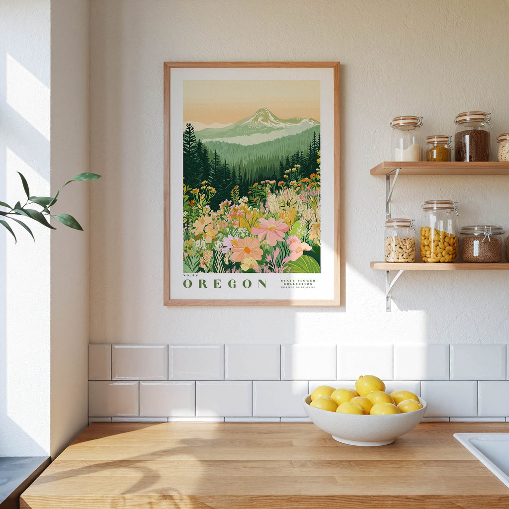 a framed poster of a mountain landscape with flowers hanging on a wall above a wooden countertop with a bowl of lemons.