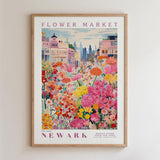 The image is a framed poster depicting a vibrant and colorful flower market in Newark, with a variety of flowers and buildings in the background.