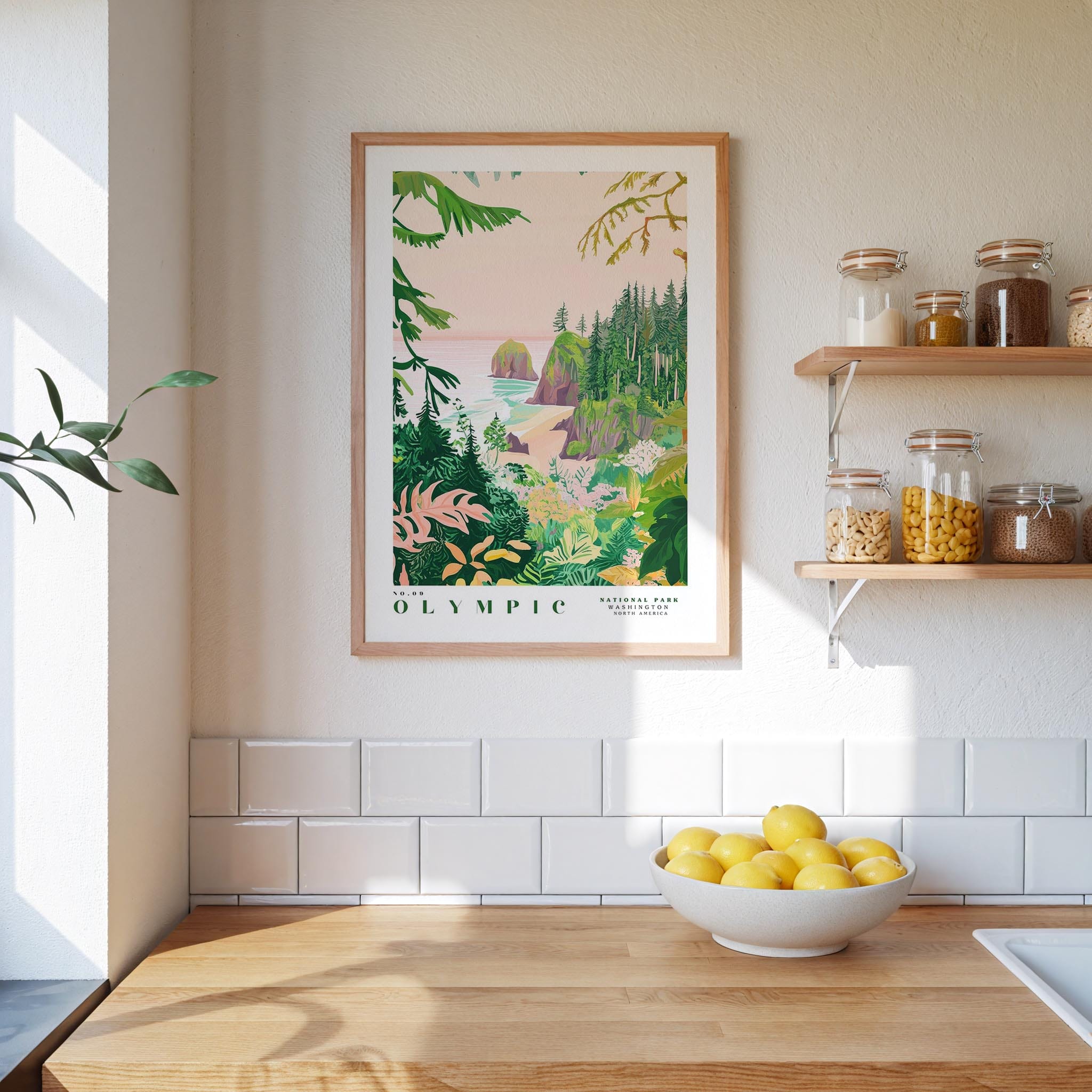 a kitchen scene with a framed poster of a tropical landscape hanging on the wall above a wooden countertop. On the countertop, there is a bowl of lemons and a plant. The kitchen also has shelves with various jars and containers, and the walls are tiled.