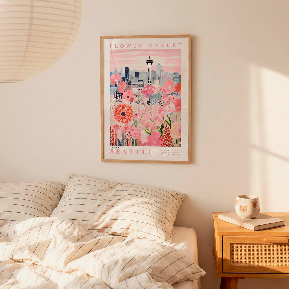 a framed poster of a cityscape with a flower market in the background, hanging on a wall above a bed with striped pillows.