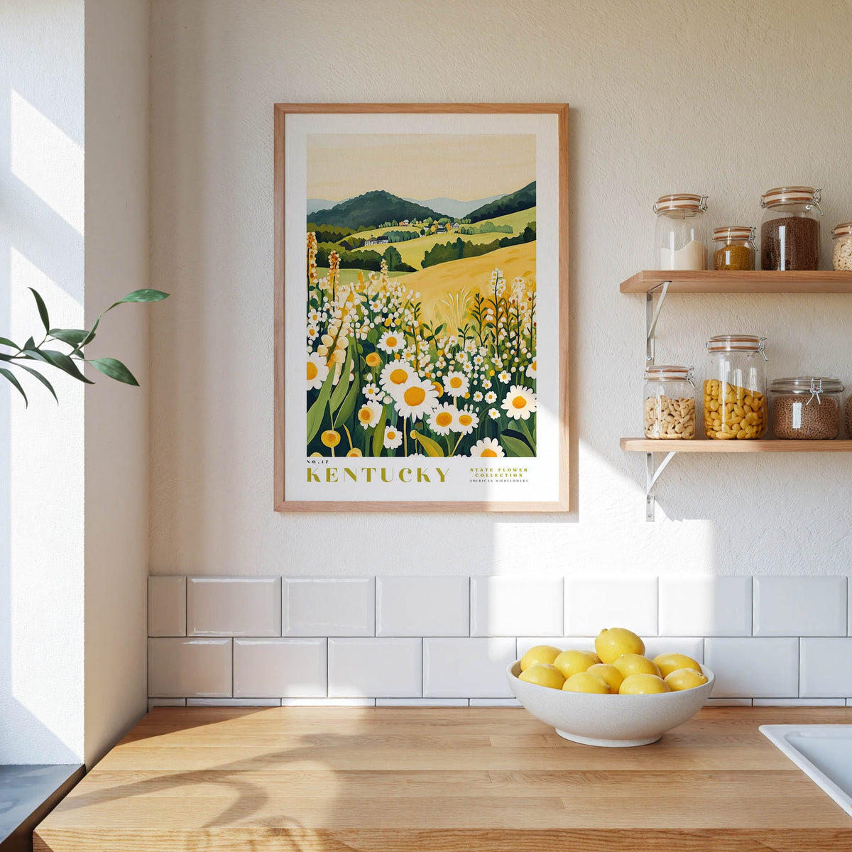 a kitchen scene with a framed print of a field of flowers hanging on the wall, a wooden counter with a bowl of lemons, and shelves displaying various jars and containers.