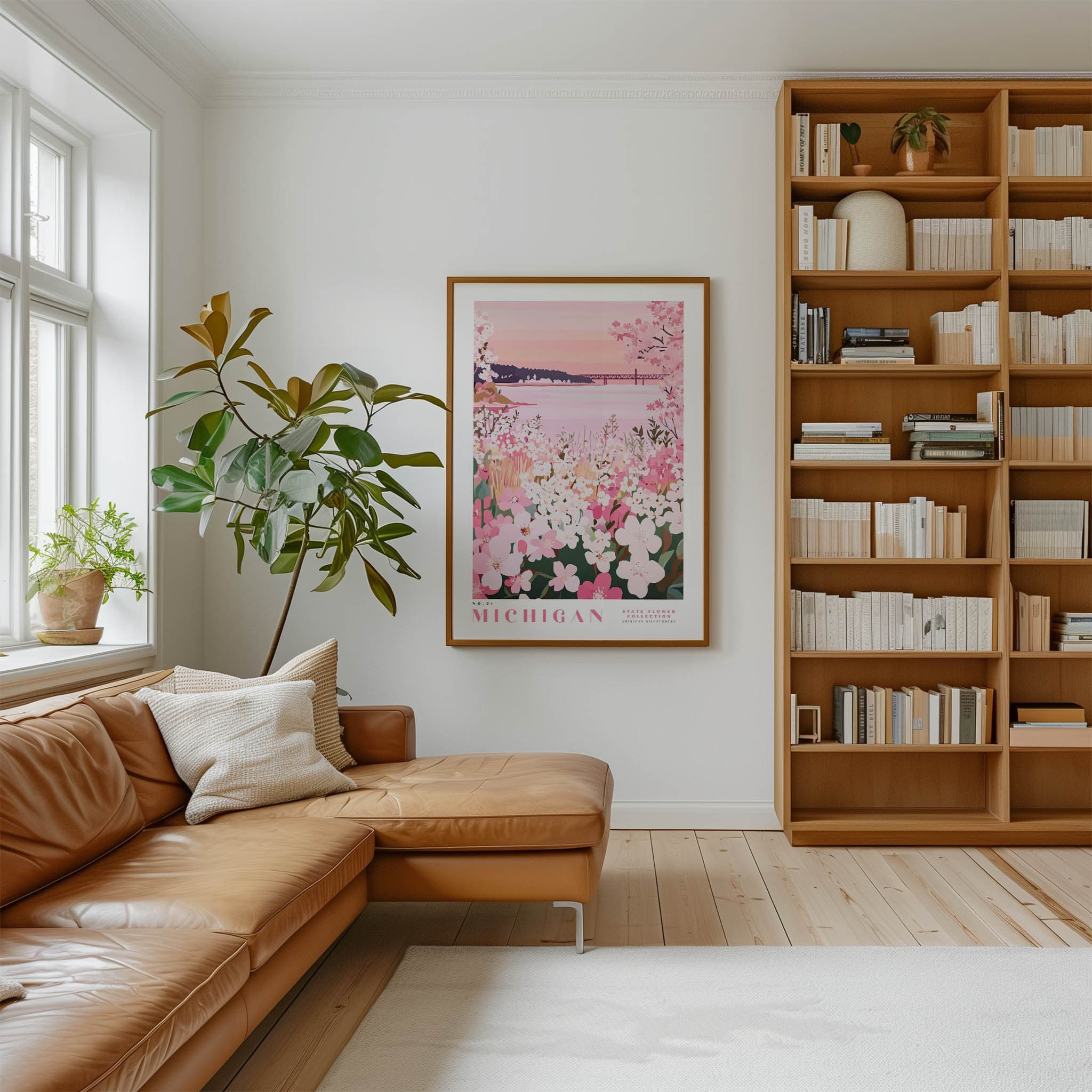 a cozy living room with a large window, a comfortable leather sofa, a wooden bookshelf filled with books, and a framed poster of a flowery landscape hanging on the wall.