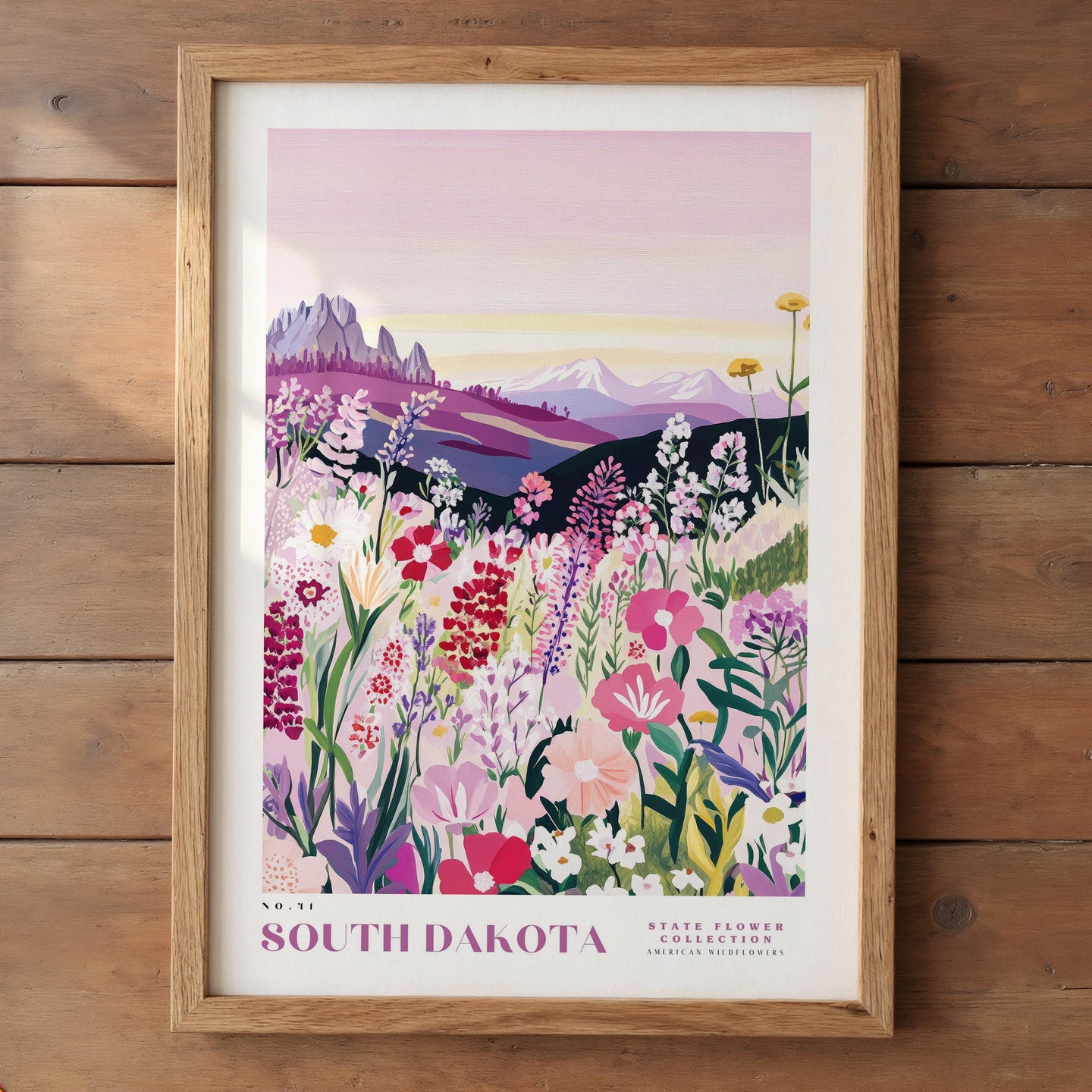 The image is a framed poster depicting a vibrant field of colorful wildflowers, with mountains in the background.