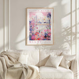 a poster of a flower market in Miami hanging on a wall above a white couch with a blanket draped over it.