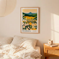 a bedroom scene with a framed poster of a field of flowers hanging on the wall above a bed with striped pillows.