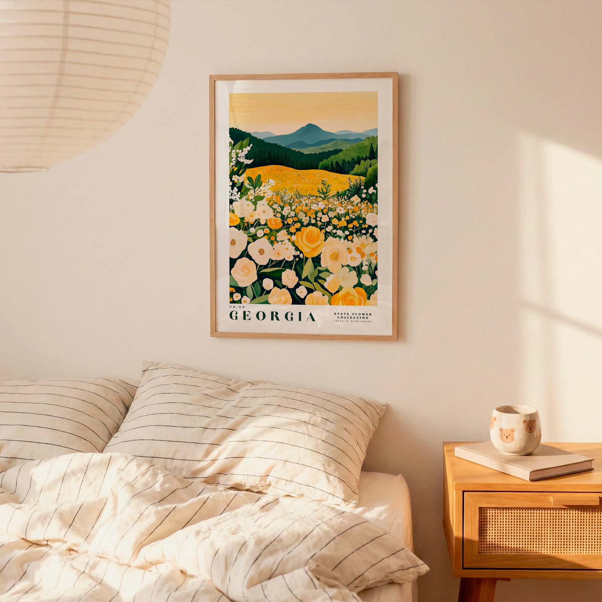 a bedroom scene with a framed poster of a field of flowers hanging on the wall above a bed with striped pillows.
