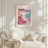 a framed poster of a beach scene with palm trees and colorful buildings, hanging on a wall above a white couch with pillows.